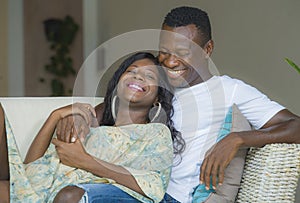 Young attractive and happy black afro American couple relaxed at home sofa couch cuddling sweet enjoying together and smiling in