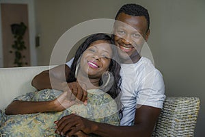 Young attractive and happy black afro American couple relaxed at home sofa couch talking sweet enjoying together and smiling in