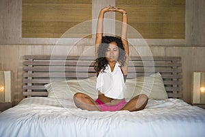 Young attractive and happy black hispanic woman at home bedroom doing joga meditation and body relaxation exercise stretching on b