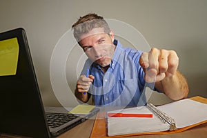 Young attractive and happy business man working with laptop computer at home office smiling satisfied and confident pointing finge