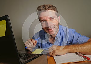 Young attractive and happy business man working with laptop computer at home office smiling satisfied and confident in successful