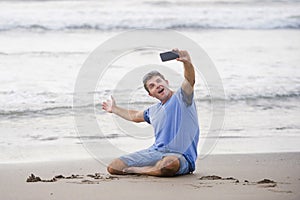 Young attractive and happy Caucasian 30s man having fun at Asian beach taking selfie picture with mobile phone smiling excited in