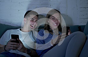 Young attractive and happy couple using internet app on mobile phone enjoying and laughing together sitting at home living room so