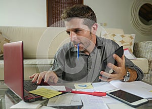 Young attractive and happy freelance business man with calculator and laptop doing domestic accounting paperwork of domestic