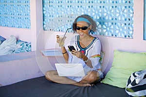 Young attractive and happy hipster Asian woman working with laptop computer and mobile phone at relaxing outdoors workplace enjoyi