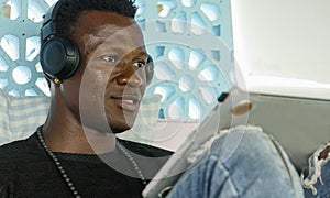 Young attractive and happy hipster black afro American business man working with laptop computer and headphones smiling satisfied