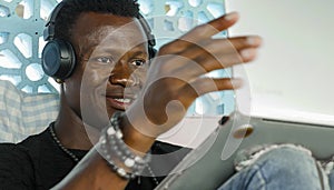 Young attractive and happy hipster black afro American business man working with laptop computer and headphones smiling satisfied