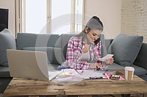 Young attractive and happy hispanic woman checking bills bank papers expenses and monthly payments smiling at apartment living roo