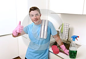 Young attractive and happy man washing with detergent spray bottle and sponge wearing gloves