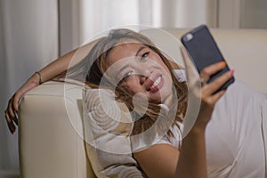 Young attractive happy and relaxed student Asian woman enjoying homey lying at living room sofa couch using internet social media