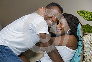 Young attractive and happy romantic afro American couple in love lying playful cuddling at living room couch playing together