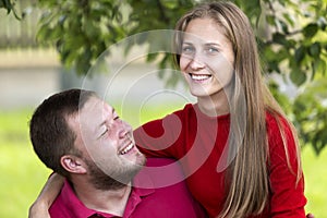 Young attractive happy romantic couple, pretty blond long-haired smiling girl and laughing unshaven man hugging together outdoors