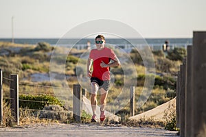 Young attractive and happy sport runner man with fit and strong healthy body training on off road track in Summer running workout