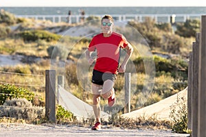 Young attractive and happy sport runner man with fit and strong healthy body training on off road track in Summer running workout
