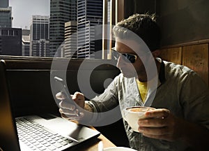 Young attractive happy and successful young businessman working relaxed from internet coffee shop with laptop computer and mobile