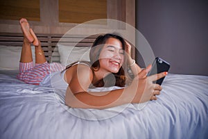 Young attractive and happy teenager woman lying relaxed and smiling cheerful in bed using internet social media or online dating