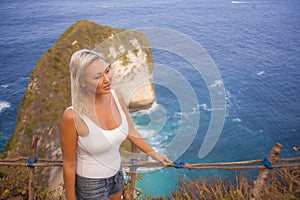 Young attractive and happy tourist woman looking the stunning view of beautiful sea cliff beach at viewpoint enjoying exotic