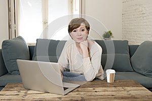 Young attractive and happy woman at home sofa couch doing some laptop computer work smiling relaxed in entrepreneur lifestyle