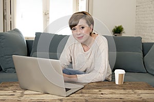 Young attractive and happy woman at home sofa couch doing some laptop computer work smiling relaxed in entrepreneur lifestyle