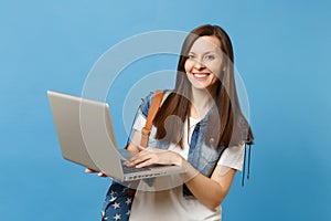 Young attractive happy woman student in denim clothes with backpack holding and using working on laptop pc computer