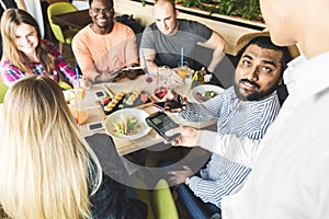 Young attractive Hindu man paying in cafe with contactless smartphone payment