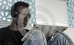 Young attractive and hipster black African American business man working with laptop computer and headphones concentrated and