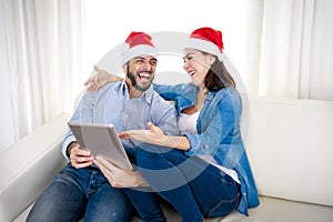Young attractive Hispanic couple in love online Christmas shopping digital tablet