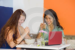 Young attractive hispanic girl sitting at modern cafe having lunch with happy woman as girlfriends meeting for discussing project