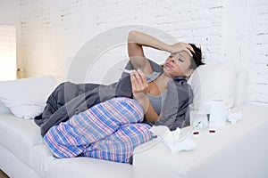 Young attractive hispanic woman lying sick at home couch in cold and flu in gripe disease symptom