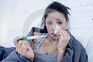 Young attractive hispanic woman lying sick at home couch in cold and flu in gripe disease symptom