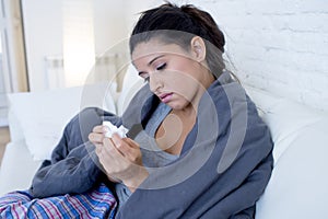 Young attractive hispanic woman lying sick at home couch in cold and flu in gripe disease symptom