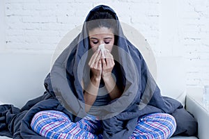 Young attractive hispanic woman lying sick at home couch in cold and flu in gripe disease symptom photo