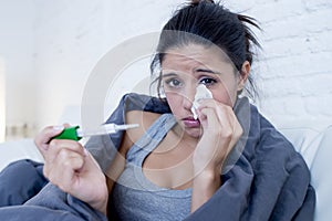 Young attractive hispanic woman lying sick at home couch in cold and flu in gripe disease symptom photo