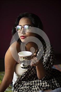 Young Indian brunette woman in white sleeping wear reading book on a bed