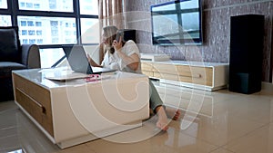 Young Attractive Lady Sits On Floor, Speaks On Smartphone, Works Overtime With Laptop And Documents
