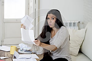 Young attractive latin woman at home living room couch calculating monthly expenses worried in stress