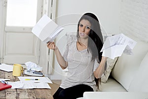 Young attractive latin woman at home living room couch calculating monthly expenses worried in stress