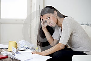 Young attractive latin woman at home living room couch calculating monthly expenses worried in stress