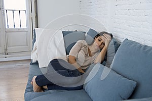 Young attractive latin woman lying at home couch worried suffering depression feeling sad and desperate