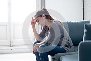 Young woman suffering from depression feeling sad and lonely on sofa at home photo