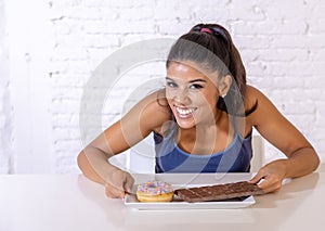 Portrait of young happy woman eating delighted chocolate bar and donuts