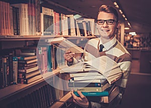 Young attractive librarian holding a pile of books in the university library.