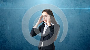 Young attractive longhair businesswoman in suit stressed and holding her head in fatigue, isolated studio background