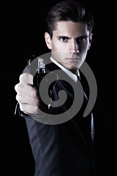 Young attractive macho in suit with gun