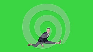 Young attractive male dancer in the strict business suit dancing making a split on a Green Screen, Chroma Key.