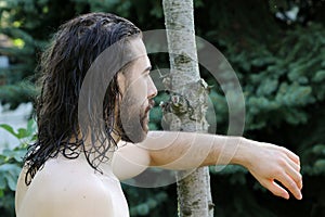 Young, attractive male model with long hair and beard posing in nature.