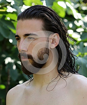 Young, attractive male model with long hair and beard posing in nature.
