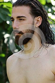 Young, attractive male model with long hair and beard posing in nature.