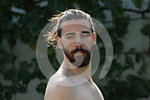 Young, attractive male model with long hair and beard posing in nature.