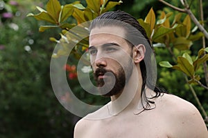 Young, attractive male model with long hair and beard posing in nature.